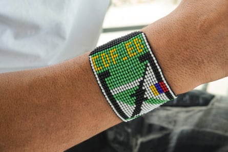 A beaded wristband on a wrist showing the logo of the armed group