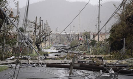 Electricity poles and lines lie on the road after Hurricane Maria hit
