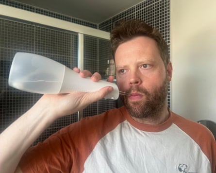 A man using a water flosser in his bathroom