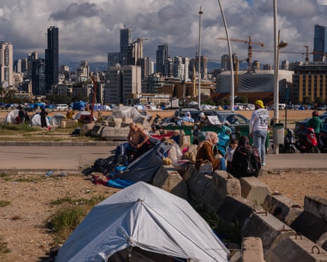 विस्थापित लोग बेरूत के समुद्री तट पर बने एक अनौपचारिक शिविर में अपने तंबू के बाहर बैठे हैं