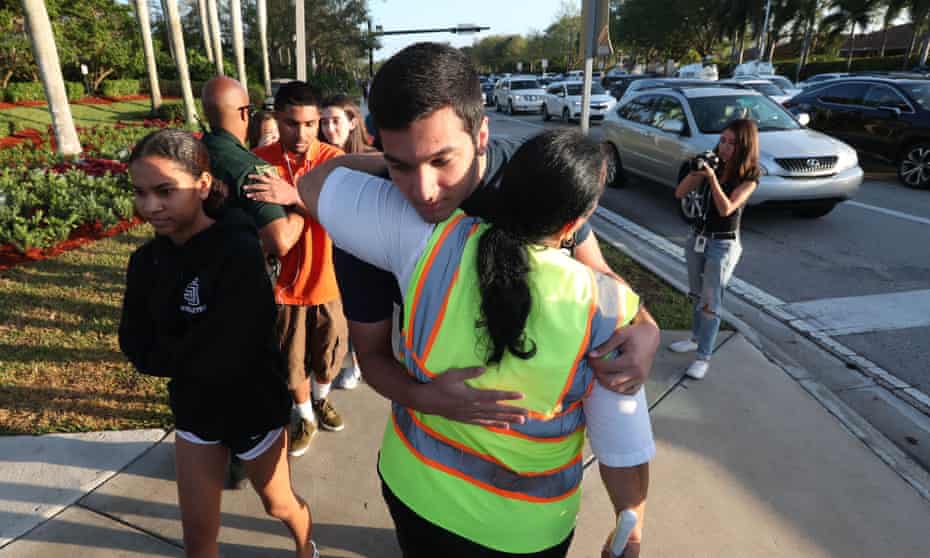 A crossing guard hugs a student as he walks to Marjory Stoneman Douglas high school for the first day of school since the shooting.  A crossing guard hugs a student as he walks to Marjory Stoneman Douglas high school for the first day of school since the shooting.