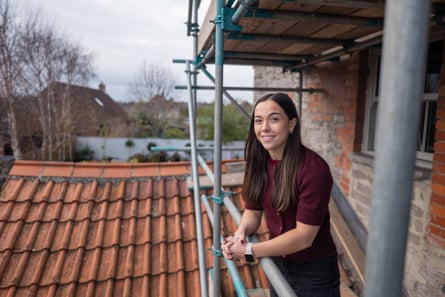 Helps stands on scaffolding erected around a house