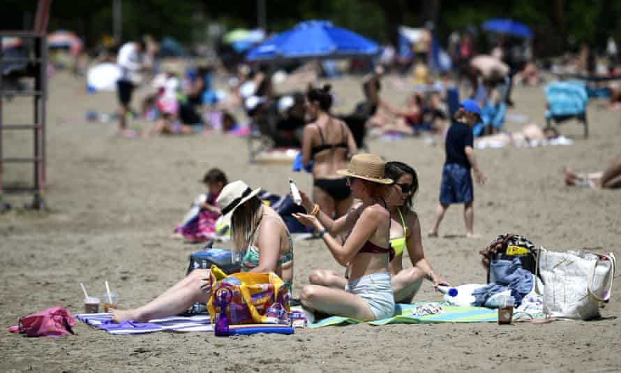People apply sunscreen while enjoying the warm weather on Mooney's Bay beach in Ottawa in June
