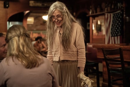 A woman with long grey-blond hair talking to another blond woman whose back is to the camera