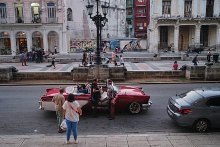 People get out of a large open-top car in a square in an old quarter of Havana