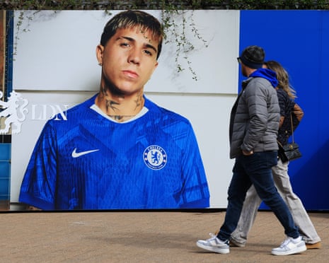 Chelsea fans walking past a picture of Enzo Fernandez outside Stamford Bridge