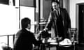 black and white film still of man handing something to another man in an office