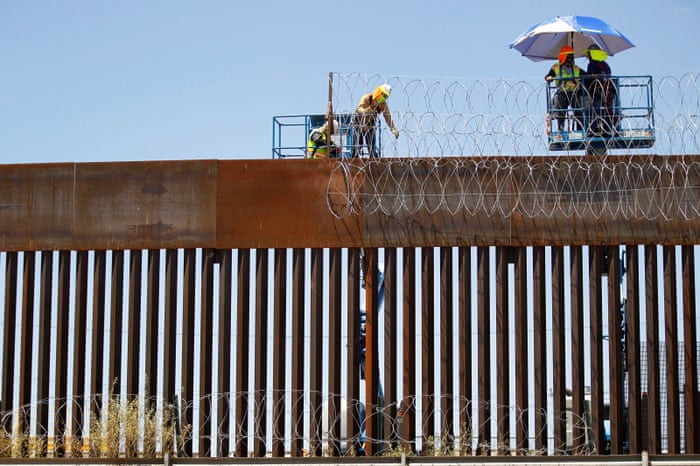 A group of workers reinforces security with barbed wire along a US border wall in Ciudad Juarez, Mexico.