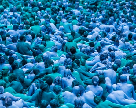 A group of naked people covered in blue paint sitting close together A group of naked people covered in blue paint sitting close together