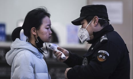 Security personnel check the temperature of passengers in the Wharf at the Yangtze River in China following the coronavirus outbreak