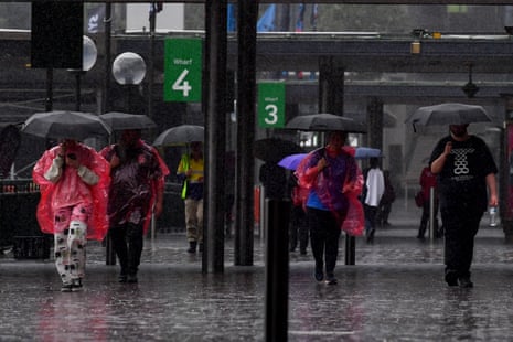 People huddle under umbrellas as they walk through heavy rain in Sydney