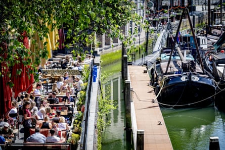 A terrace packed with people eating and drinking on the edge of a harbour