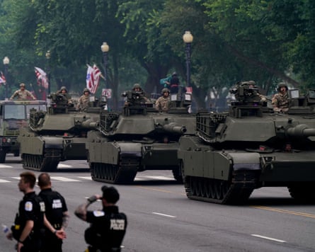 Tanks driving along a street with police officers in the foreground