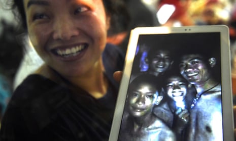 A happy family member shows the latest picture of the missing boys taken by rescue divers inside the cave