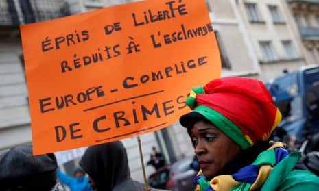 A woman holds a placard as she attends a protest against slavery outside the Libyan embassy in Paris.