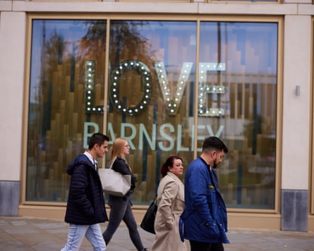 People passing a giant Love Barnsley sign in a shop window in Barnsley, South Yorkshire