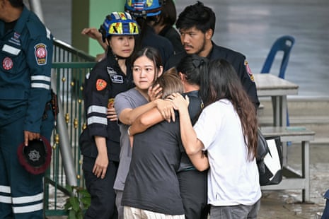 People console the wife of a teacher who was killed in the school shooting in Bang Kruai district.