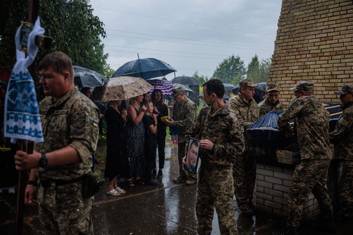 Family members receive a Ukrainian national flag during the funeral of Ukrainian serviceman Anton Savytskyi at Bucha’s cemetery in Kyiv region on 13 August, 2022, amid the Russian military invasion of Ukraine.
