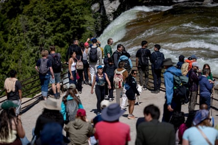 Crowds of group successful hiking cogwheel opinionated astatine nan apical of a cliff arsenic a waterfall plunges over.