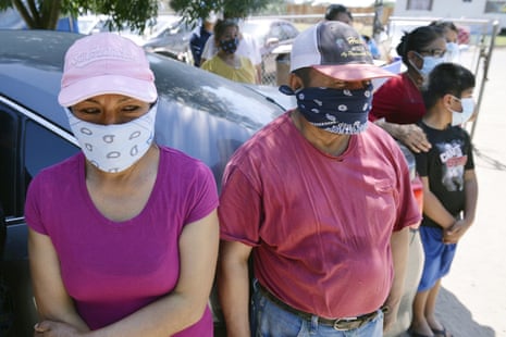 Masked farmworker families stand waiting for donated food near Rolinda, in Fresno county, in May.