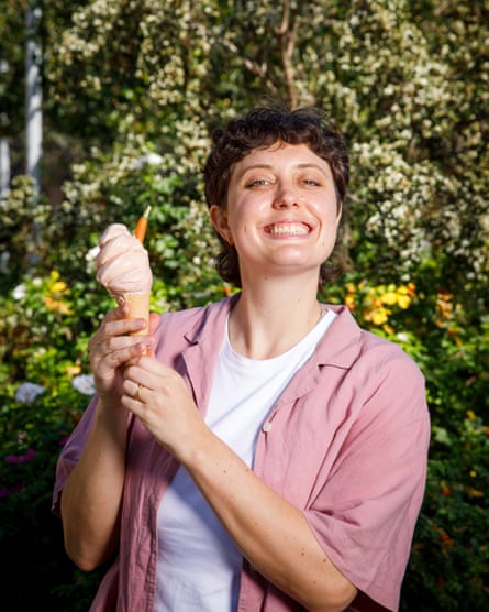 Lucy Knight in a white T-shirt and pink shirt smiles as she holds up an ice-cream cornet.
