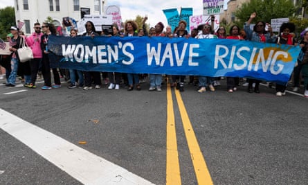 Women marching with a banner reading ‘Women’s Wave Rising’