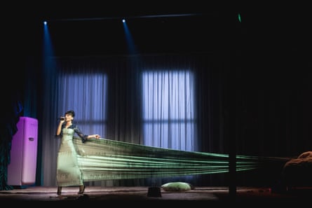 A woman on stage pulling a long length of material behind her - stretched out