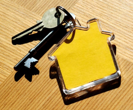 House keys and house-shaped keyring on wooden table.