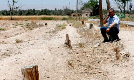 A man sits on a barren piece of farmland in Eastern Ghouta, Syria.
