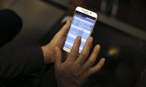 An Iranian shareholder monitors stock prices on his mobile phone.