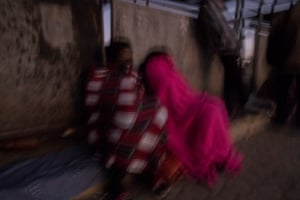 Mupombwi, right, takes a nap while waiting for the bus to work in the city