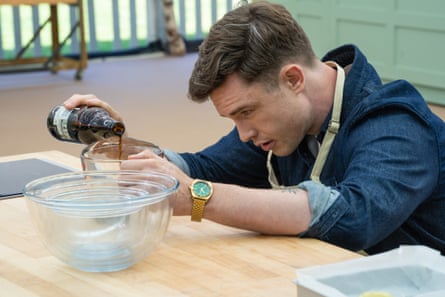 Ed Gamble leans over a table, pouring dark liquid from a bottle into a glass bowl