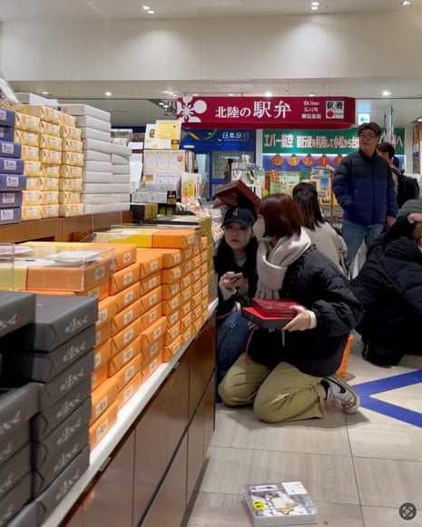 People sit on the floor as items fall from shelves inside a store as an earthquake hits in Kanazawa, Ishikawa.
