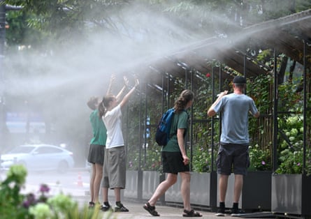 People stand in a mist-spraying zone to cool off on a street in Seoul