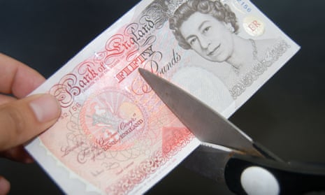 Fifty pound note being cut with scissors