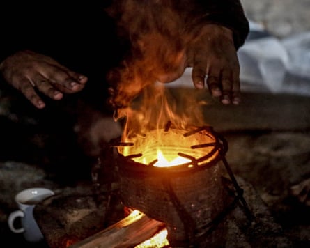 Hands held out towards a small makeshift stove.