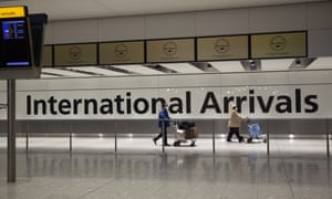 Passengers walk past a sign in the arrivals area at Heathrow Airport in London.