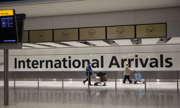 Passengers walk past a sign in the arrivals area at Heathrow airport