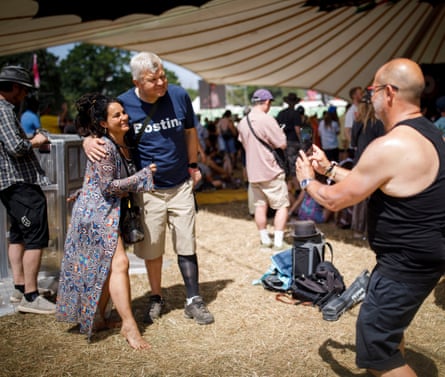 He poses for a photo with a woman, while a man snaps the picture