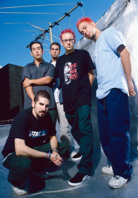 Five men standing on a roof. Two of them have pink hair.
