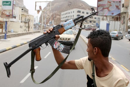 A member of Yemen’s southern separatist holds his weapon with a picture of Bridgadier General Muneer al-Yafee, killed in a Houthi missile attack, in Aden.
