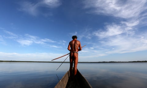 Ecutia, one of the best fishermen in the village, fishes with a traditional bow and arrow in a dugout canoe in the village of Kamayura, in Xingu national park, Brazil, in 2013.