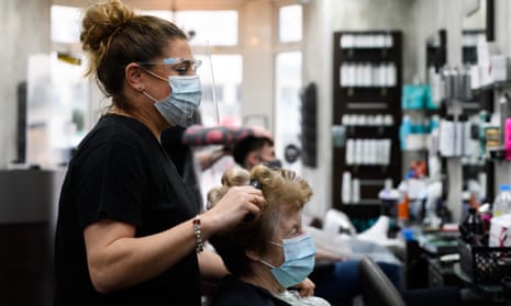 Masked hairstylist cuts hair of masked customer
