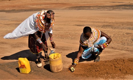 Paulina Lekureiya and Kareni Lematile scooping out sand to make a hole for underground water to collect