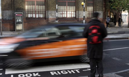 A man with a rucksack waits to cross a zebra crossing