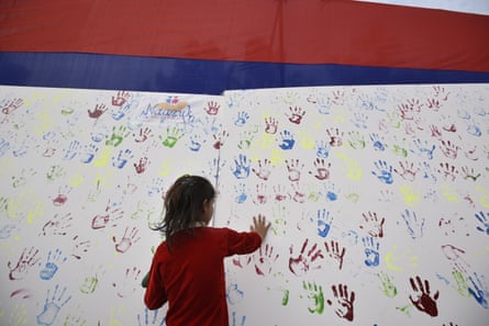 A girl adds her handprint to an art installation during an awareness campaign for missing children.