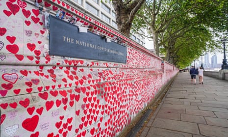People walk past the national Covid memorial wall painted with red and pink hearts containing the names of people who died