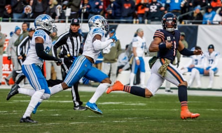 Justin Fields (a destra) si guarda alle spalle mentre lascia i difensori dei Lions.