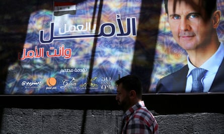 A man walks past a banner depicting Syria’s president, Bashar al-Assad, in Damascus