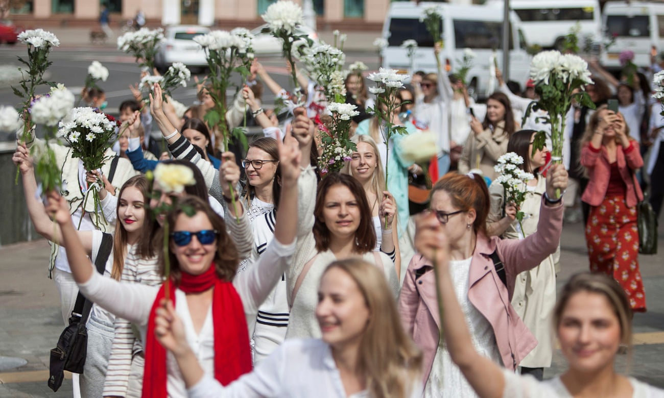 Women wearing white and waving flowers take part in a procession against police violence in Minsk.